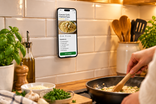 Visuel IA : un téléphone affiche une recette sur le carrelage d’une cuisine.