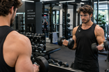 Visuel IA : un homme se filme avec un téléphone sur un miroir de salle de sport.